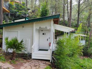 a small white shed with a door in the woods at Kasauli Hills Resort in Kasauli