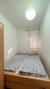 Cama grande en habitación pequeña con ventana en Lorono Kosta, en Belgrado