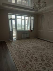 an empty room with a large rug and a large window at ELSAR guesthouse in Osh