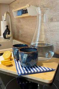 a glass vase and two cups on a cutting board at Powder Blue Studio in Gdańsk