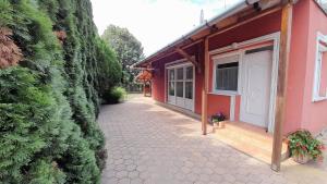 a walkway next to a house with a green hedge at Iza Vendégház in Hajdúszoboszló