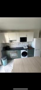 a kitchen with white appliances and a wooden table at 5 minutes à Pied du Stade De France in Saint-Denis