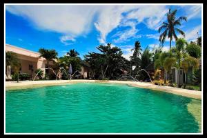 una grande piscina di acqua verde di fronte a una casa di Imagine-Bohol a Panglao