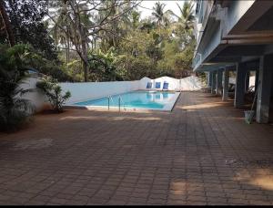 una piscina con sillas azules junto a un edificio en Sea Mist Apartment, en Candolim