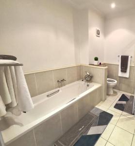 a white bathroom with a tub and a toilet at Luxury Lifestyle Villa in Mossel Bay