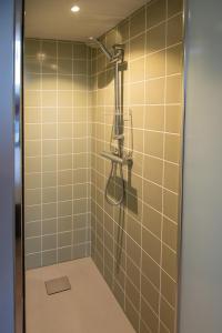 a bathroom with a shower with tan tiles at B&B de oude melkfabriek in Valkenswaard