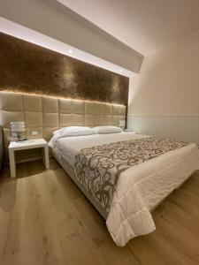 a bedroom with a large bed with a large headboard at Hotel Conca Verde in Lignano Sabbiadoro