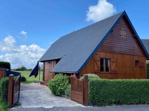a large wooden barn with a black roof at Chalet 6 pers avec piscine in Cabourg