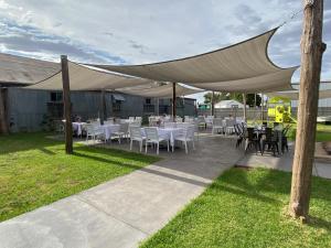 a patio with white tables and chairs under a tent at Commercial Hotel Lockhart in Lockhart