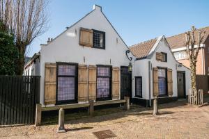 uma antiga casa branca com janelas com persianas de madeira em B&B de Drukkerij Zandvoort - luxury private guesthouse em Zandvoort