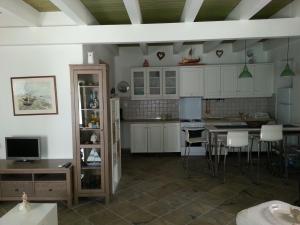 cocina con armarios blancos, mesa y sillas en Lavinia, en Gáios