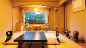 uma sala de jantar com uma mesa e cadeiras e uma janela em Bergtour Marukita em Hakuba