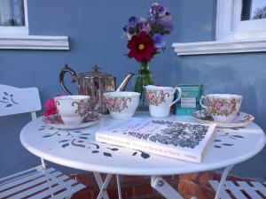 a table with a book and cups and a vase with flowers at Northampton House in Llanwrtyd Wells +1 photo