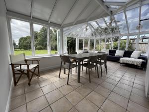 un salón acristalado con mesa, sillas y sofá en Stunning 5 bedroom country home with amazing views, en Leamington Spa