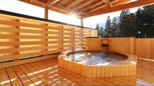 uma banheira de hidromassagem num deque com paredes de madeira em Bergtour Marukita em Hakuba