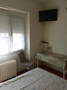 une chambre avec un bureau, un radiateur et une fenêtre dans l'établissement Chambre meublée au cœur de ville - chez l'habitant, au Creusot