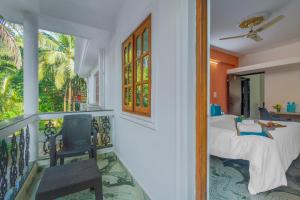 a bedroom with a balcony with a bed and a chair at The Sequeira Goa in Majorda