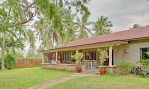 uma casa com um alpendre com palmeiras ao fundo em Salama House - your peaceful, poolside retreat em Watamu