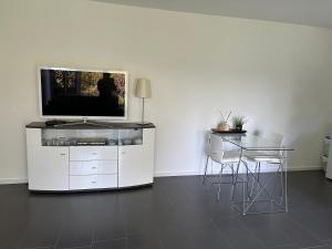 uma sala de estar com uma televisão e uma mesa com cadeiras em Homequartier Passau em Passau