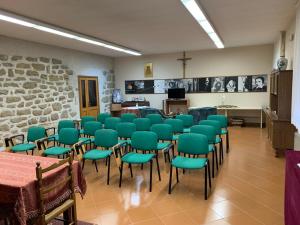 a room with green chairs and tables and a stone wall at Stabat Mater Casa di Preghiera in Valdragone