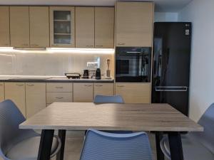 a kitchen with a wooden table and blue chairs at Ethos Apartment in Nea Peramos