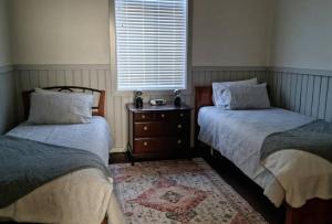 a bedroom with two beds and a dresser and a window at Millhouse on Pine in Pemberton