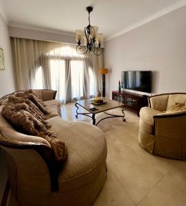 ein Wohnzimmer mit einem Sofa und einem TV in der Unterkunft Luxury 2BD flat, steps from Sahl Hasheesh beach in Hurghada