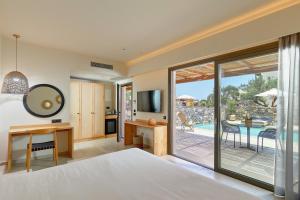 a bedroom with a bed and a view of a patio at Sentido Amounda Bay in Amoudara Herakliou