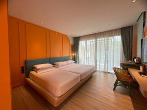 a bedroom with a large bed with a desk and a window at Banlansuan Resort SHA Plus in Cha Am