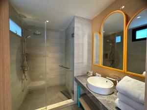ein Bad mit einem Waschbecken und einer Glasdusche in der Unterkunft Banlansuan Resort SHA Plus in Cha-am