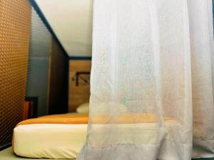 a bedroom with a bed with a white curtain at Arch Dormitorio Cenang in Pantai Cenang