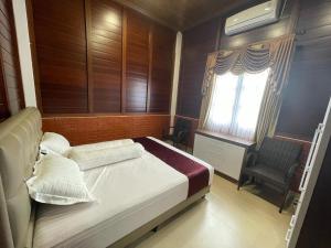 een slaapkamer met een bed, een raam en een stoel bij Villa Arjuna 