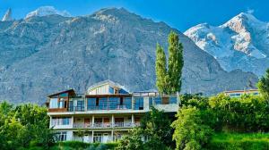 a house in front of a mountain with mountains in the background at Backpackers Stories by Old Hunza Inn in Hunza