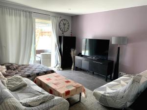 ein Wohnzimmer mit einem Sofa und einem TV in der Unterkunft Jolie villa a 10 minutes de la mer pour vos vacances in Sauvian
