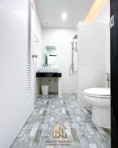 La salle de bains blanche est pourvue de toilettes et d'un lavabo. dans l'établissement นครพนม นอร์ดิกเฮ้าส์, à Nakhon Phanom