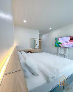 1 dormitorio con 1 cama blanca grande y TV en la pared en นครพนม นอร์ดิกเฮ้าส์ en Nakhon Phanom