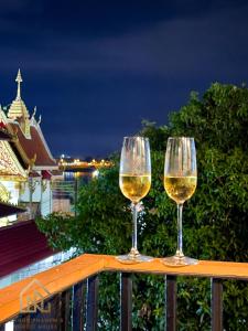 two glasses of white wine sitting on a railing at นครพนม นอร์ดิกเฮ้าส์ in Nakhon Phanom