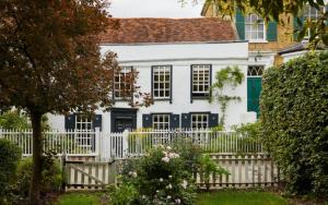 a white house with a white picket fence at Clarendon Cottage in Enfield