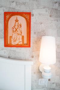 una pintura de una diosa en una pared junto a una lámpara en B&B La Chora Di Paestum, en Paestum