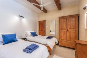 sypialnia z 2 łóżkami i drewnianą szafką w obiekcie Dar ta' Mansi Farmhouse with Private Pool w mieście Għarb