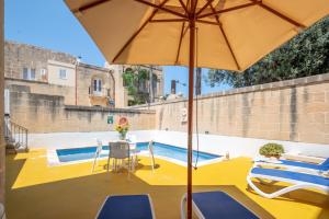 żółte patio ze stołem i parasolem w obiekcie Dar ta' Mansi Farmhouse with Private Pool w mieście Għarb