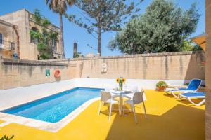 patio ze stołem i krzesłami przy basenie w obiekcie Dar ta' Mansi Farmhouse with Private Pool w mieście Għarb