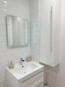 a white bathroom with a sink and a mirror at Chic and Airy Apartment in Royal Tunbridge Wells