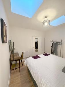 a white bedroom with a bed and a chair at Chic and Airy Apartment in Royal Tunbridge Wells
