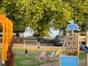 dos niños jugando en un parque con sillas de jardín en Baltica Mielenko - domki apartamentowe nad morzem, en Mielenko