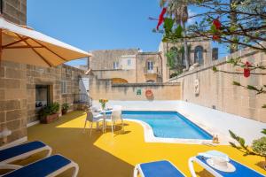 a patio with a pool and chairs and a table at Gozo Escape in Għasri