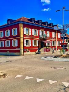 un gran edificio rojo con una calle delante en Hotel de ville d'Yvonand en Yvonand