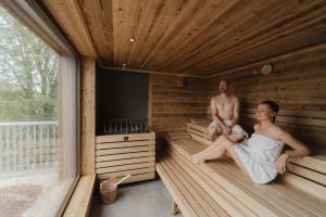 un homme et une femme assis dans un sauna dans l'établissement Landhotel Schwabenhof, à Heiligenbrunn