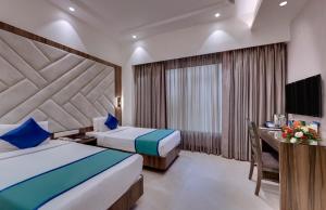 a hotel room with two beds and a desk at Hotel Suba Star Ahmedabad in Ahmedabad