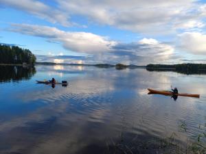 アーネコスキにあるAccommodation and Fishing Vonkaleの三人が湖の上で船に乗っている